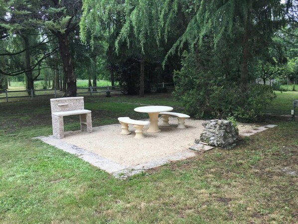 A picnic area with a stone bench, a round table, and two benches.