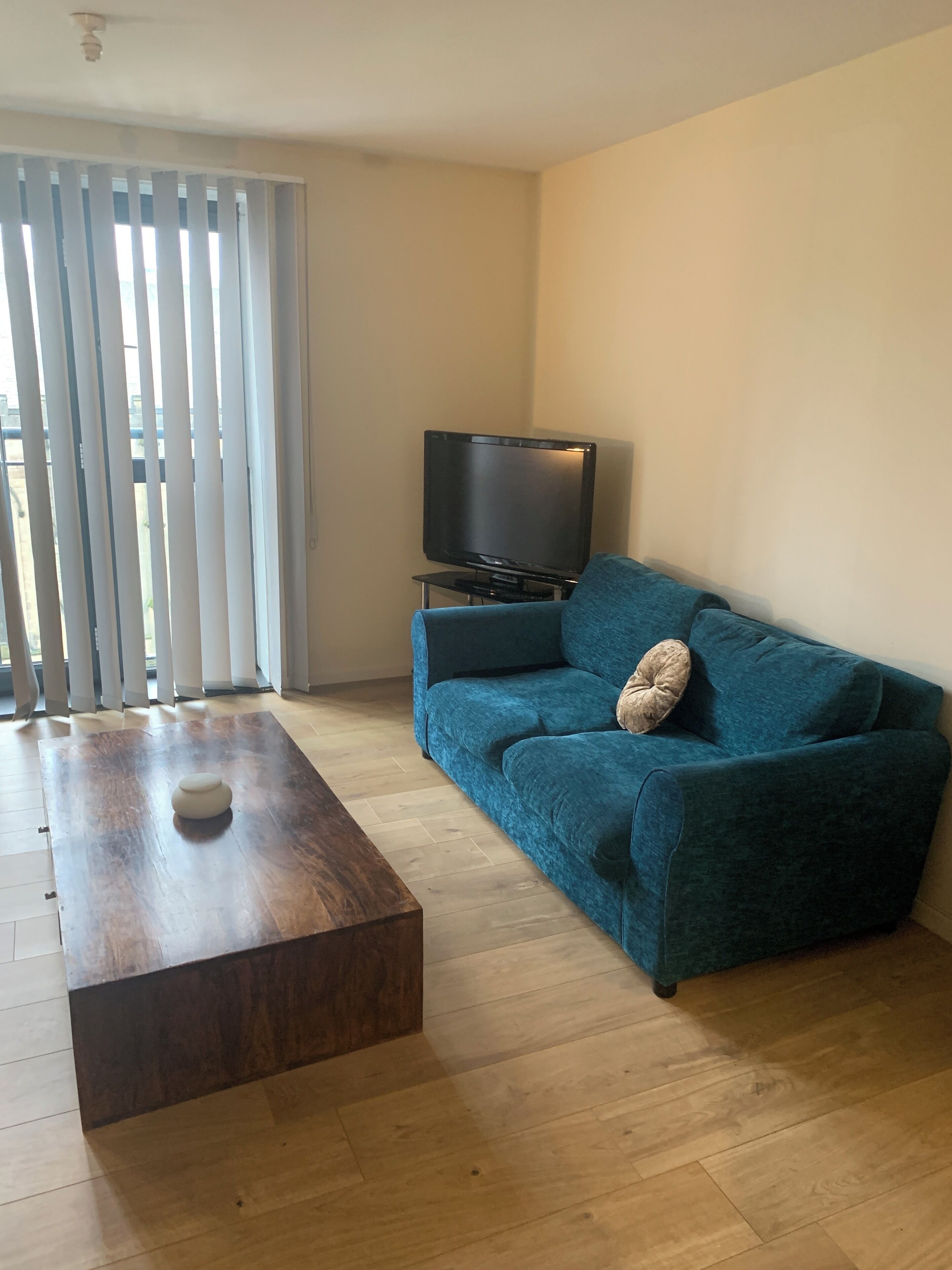 A living room with a blue sofa, a wooden coffee table, and a television on a stand.