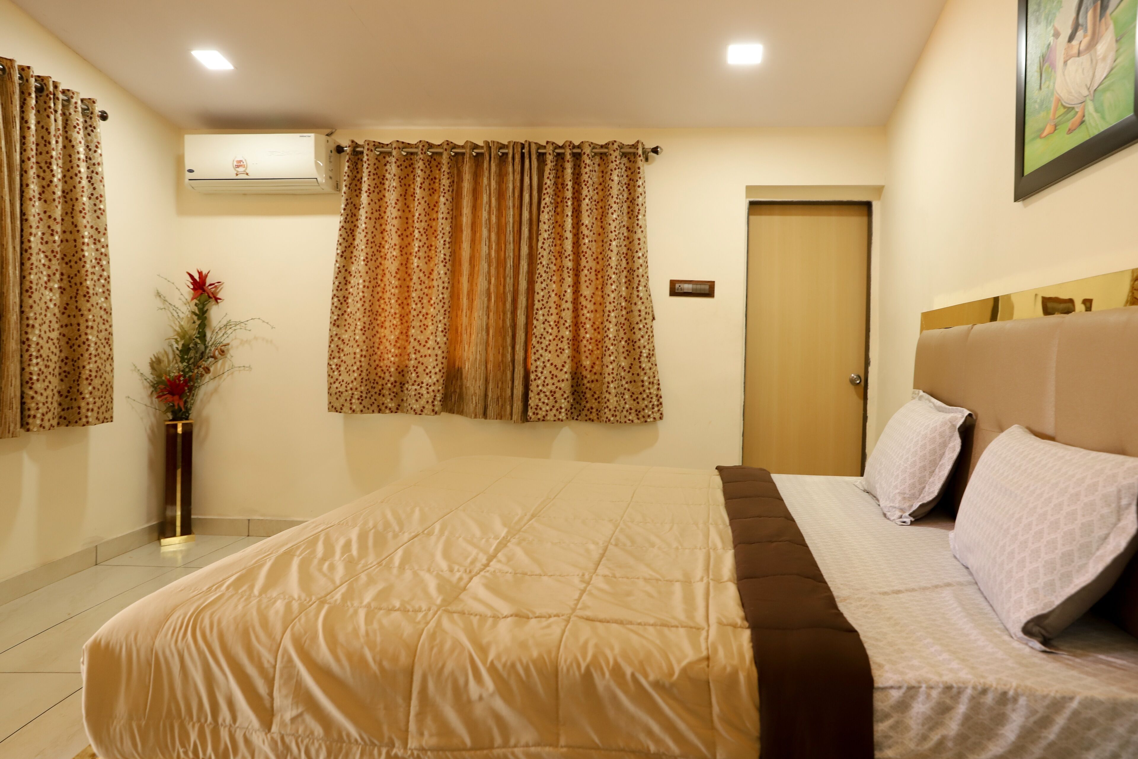 A hotel room with a large bed, a bedside table with a vase, and a door with a sign.