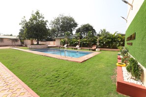 Ein Garten mit Swimmingpool, Rasenfläche und einem Gebäude mit grüner Wand.