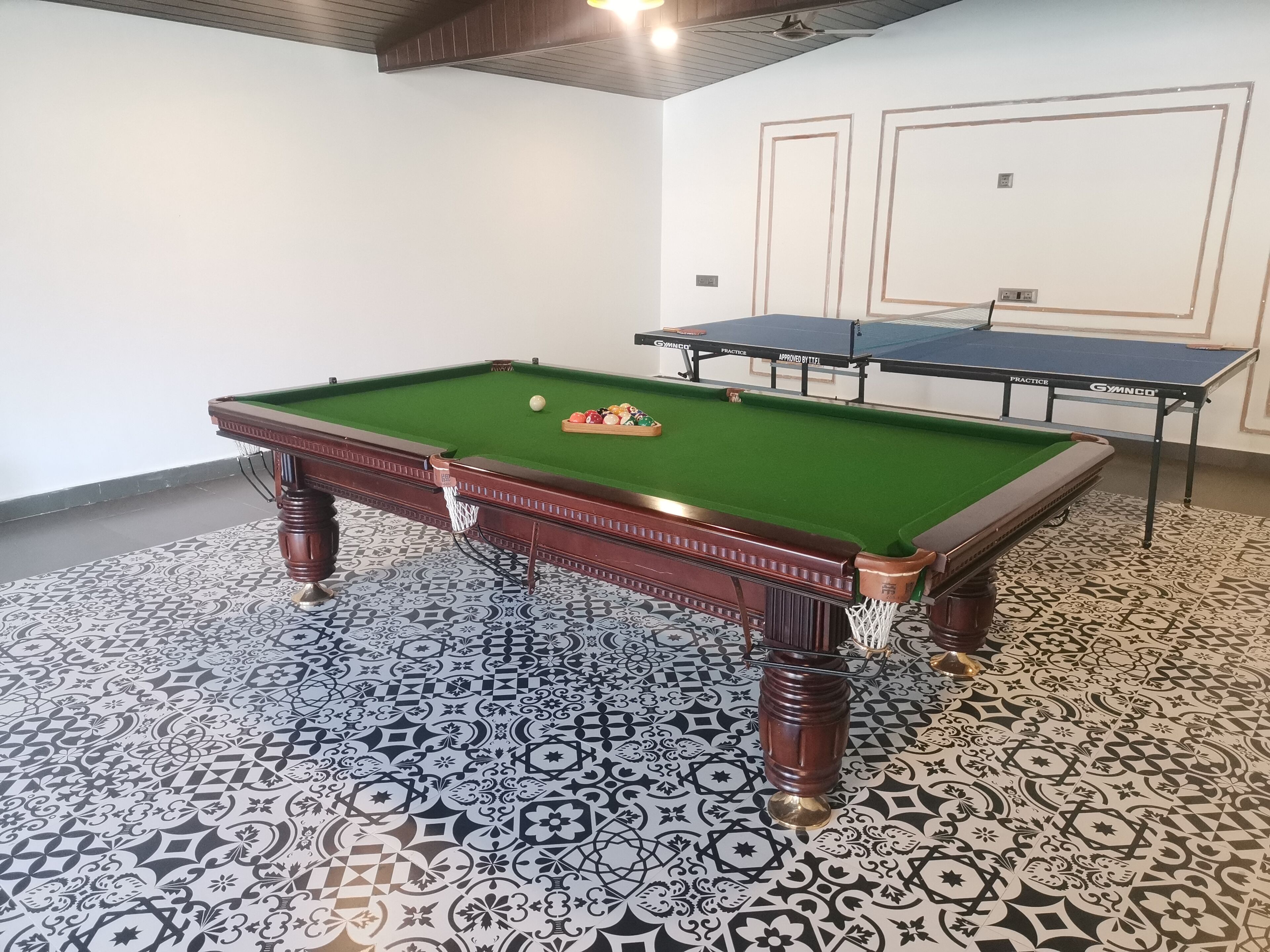 Una mesa de billar con superficie de fieltro verde, una vara de billar y un juego de bolas.