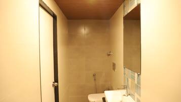 A small, narrow bathroom with a toilet, sink, and shower.