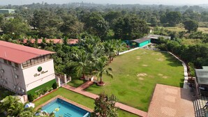 Een resort met een zwembad, een tennisbaan en weelderige begroeiing.