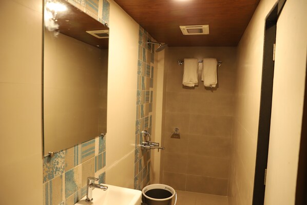 Un baño con lavamanos, espejo, ducha y dos toallas colgadas en la pared.