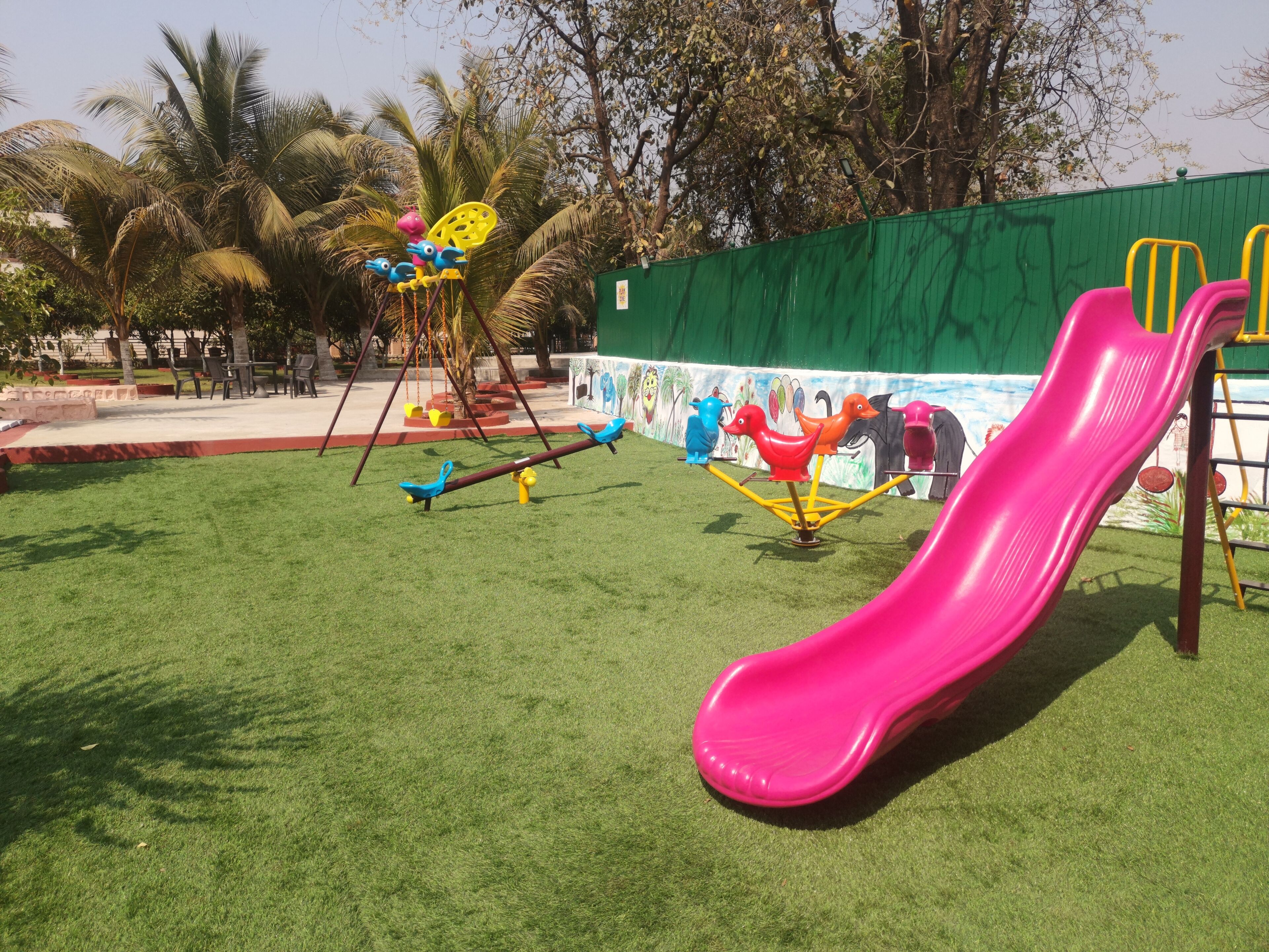 A playground with a pink slide, swings, and a seesaw.