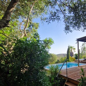 A pool area with a wooden deck, surrounded by lush greenery and trees. - Eco-villa Monte Do Barrocalinho (Loulé)