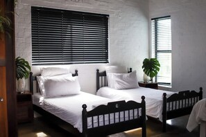A room with two beds, white bedding, and black headboards. - Family Suite w/ Pool, Hot Tub, fireplace & Valley Views (Cape Town)