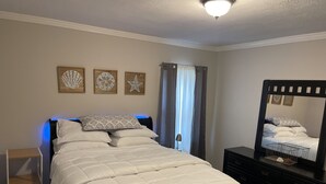 A bedroom with a bed, a bedside table, a dresser, and a mirror. - Cozy house close to everything you need for a comfortable stay. (Columbus)