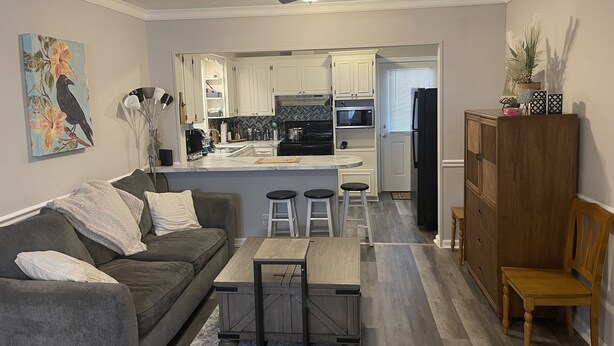 A modern living room with a grey sofa, a wooden coffee table, and a ceiling fan. - Cozy house close to everything you need for a comfortable stay. (Columbus)