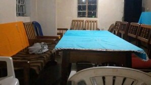 Una habitación con una mesa larga cubierta con un mantel azul, rodeada de sillas de madera y un sofá.