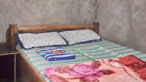 Una cama individual con cabecera de madera, dos almohadas y una colcha a rayas.