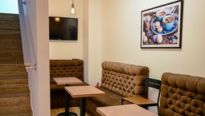 A restaurant with a staircase, cushioned seating, and a flat-screen TV on the wall. - Dona (Belgrade)