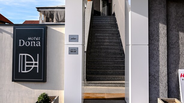 The entrance to Hotel Dona with a modern design, a staircase leading to the entrance, and a sign indicating the hotel's name. - Dona (Belgrade)