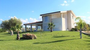 A modern house with a spacious lawn, a covered patio, and a large rock feature.