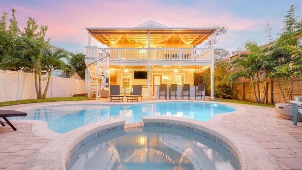 A two-story house with a swimming pool and a covered patio area.