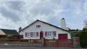 Una casa blanca con contraventanas rojas, un portón de piedra y una puerta de garaje roja.