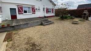 Un edificio blanco con contraventanas rojas y una terraza de madera.