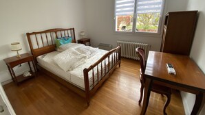 Un dormitorio con cama de madera, mesitas de noche, un escritorio y una ventana con persianas.