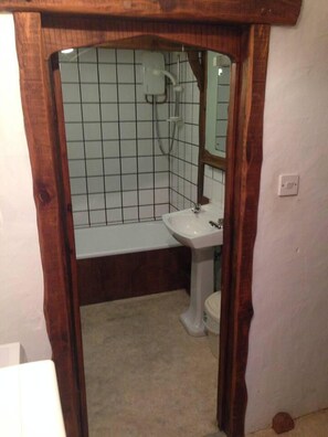 A bathroom with a wooden frame, a white sink, a mirror, and a tiled wall. - Relax in Mountain View Cottage at Cwmiar Farm (Llanybydder)