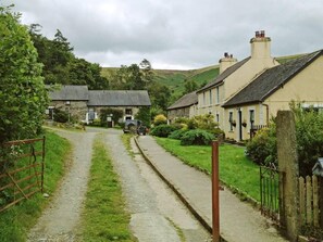 Een smalle landweg die leidt naar traditionele stenen huizen met rieten daken.