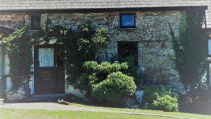 Un edificio de piedra con fachada desgastada, una ventana pequeña y una puerta.