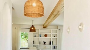 A modern kitchen with white cabinetry, a central island, and a hanging wicker pendant light.