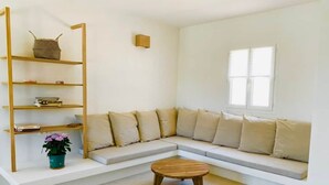 A modern living room with a sectional sofa, a wooden coffee table, a bookshelf, and a window.