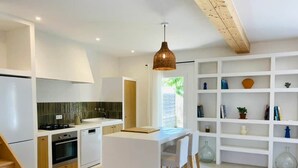 A modern kitchen with white cabinetry, a central island, and a hanging pendant light.