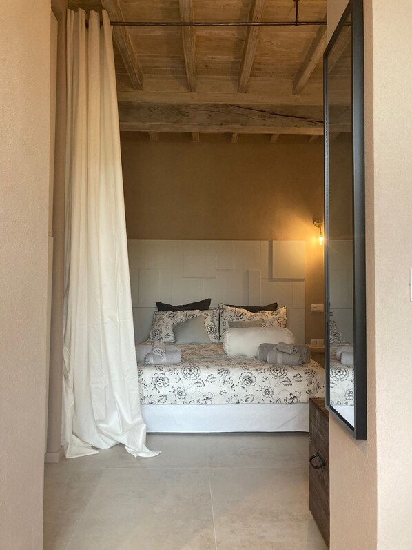 Ein Schlafzimmer mit Bett, Spiegel und Vorhang.