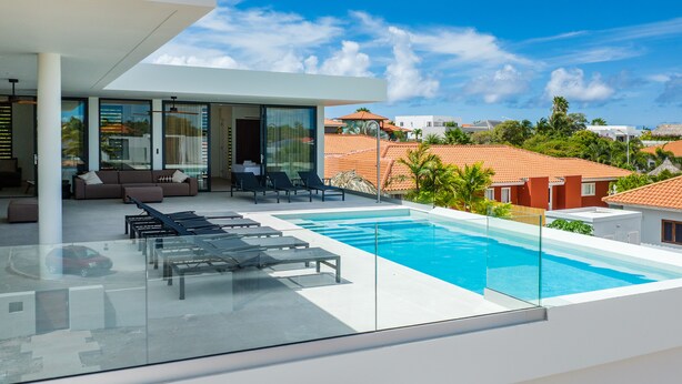 A modern outdoor pool area with lounge chairs and a glass balustrade.