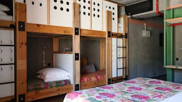 Un dormitorio con literas, una colcha acolchada y una pared verde con ventana.