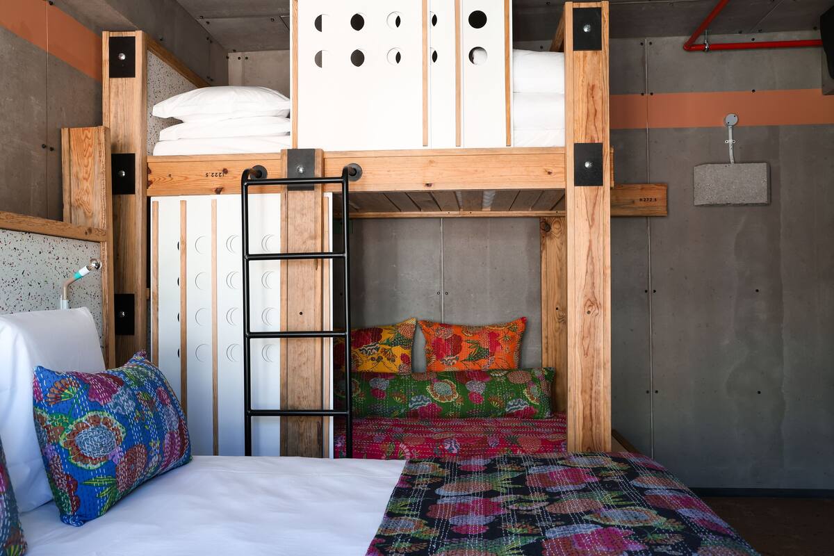 A bunk bed with a ladder, a wooden headboard, and a colorful quilt.
