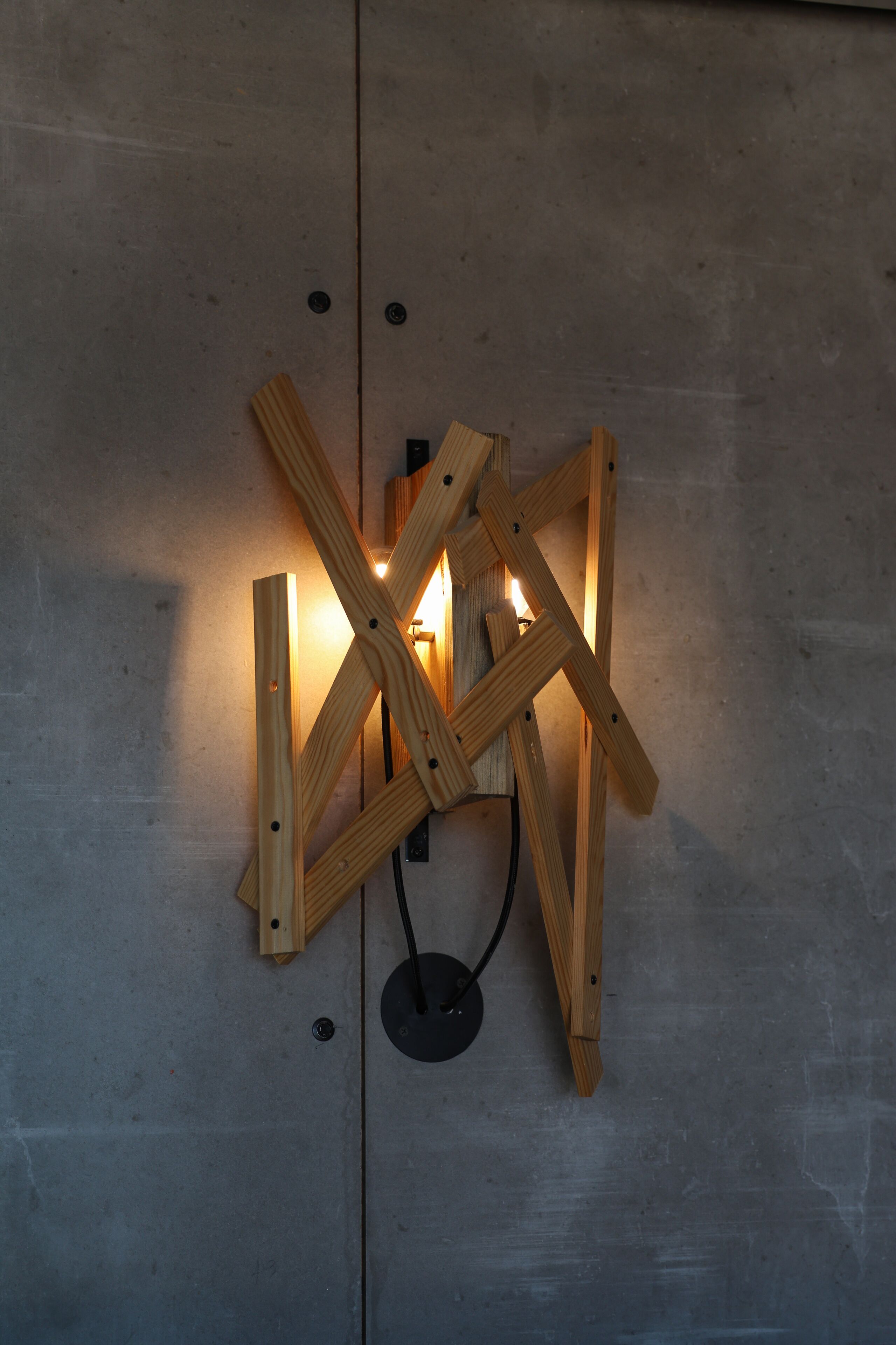 Una lámpara de madera fijada a la pared, con base circular y cable de alimentación.