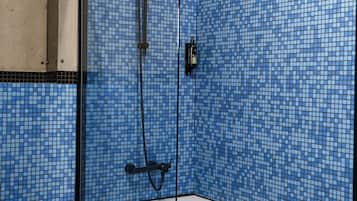 Ein Badezimmer mit einer weißen Badewanne, blauen Mosaikfliesen und einer Duschkabine mit einem schwarzen Brausekopf.