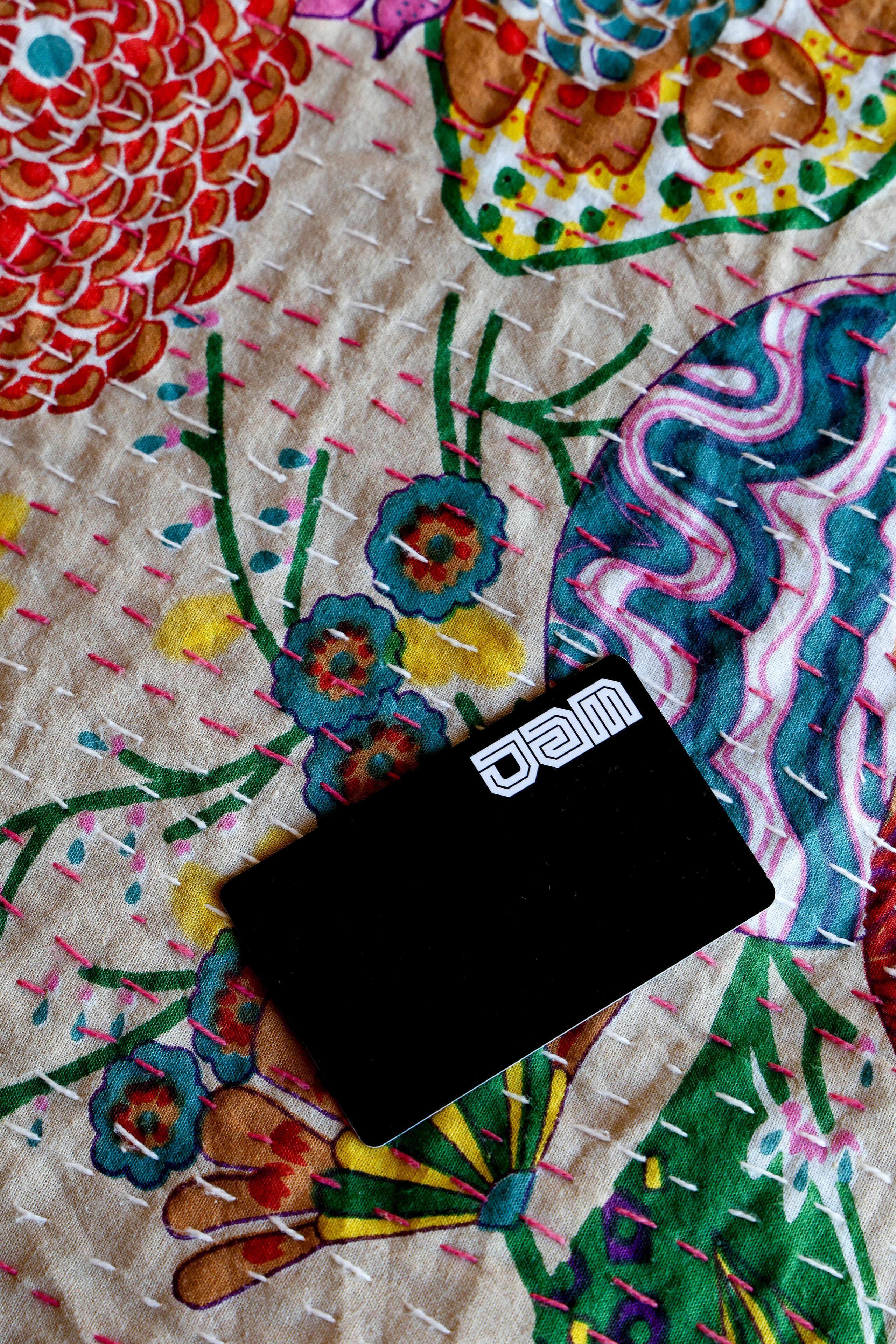A black object with "jam" on it, placed on a colorful fabric with floral patterns.