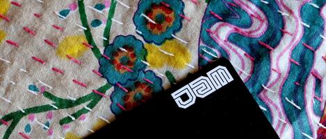 Un objeto negro con la palabra "jam" sobre él, sobre una tela colorida con motivos florales.