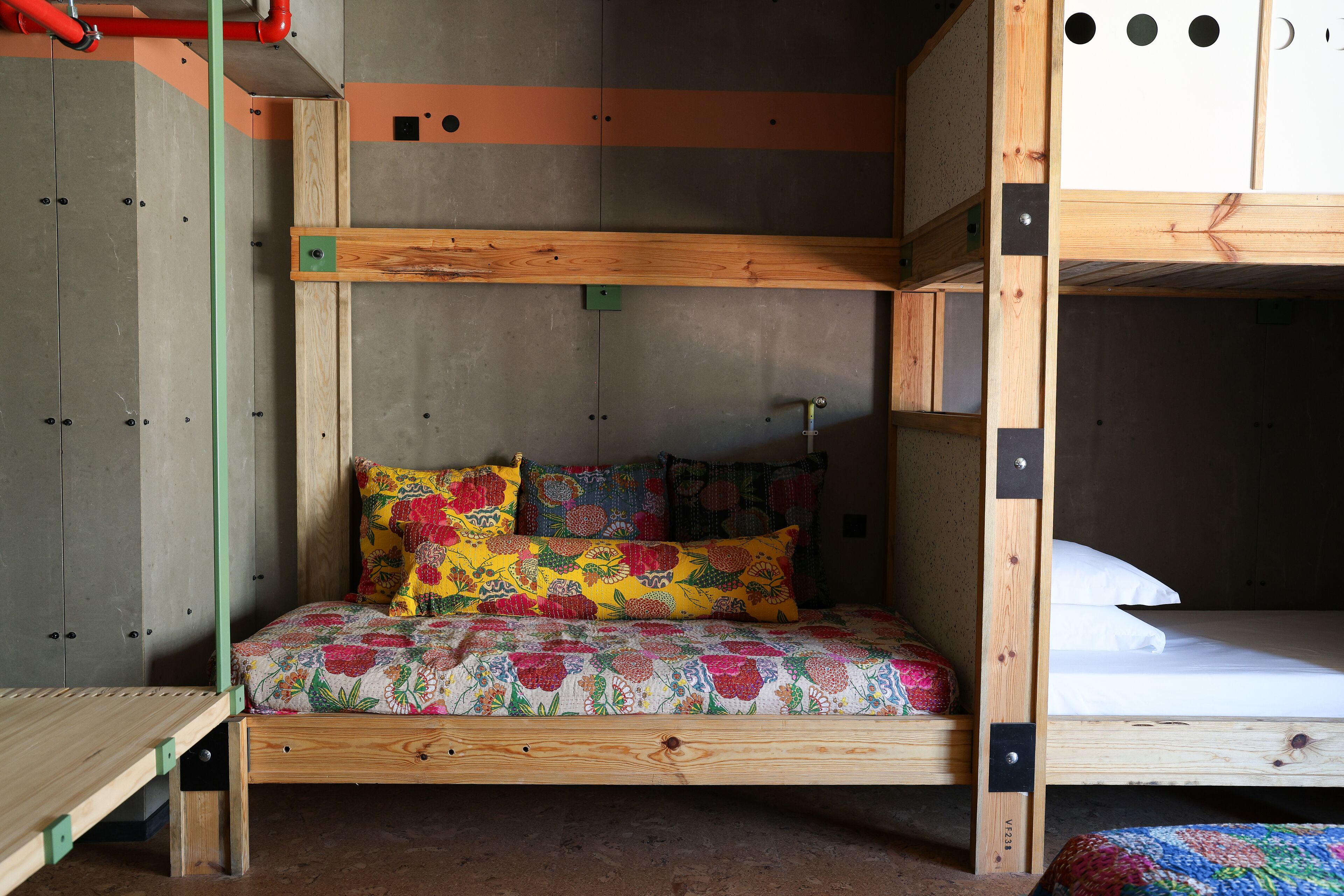 Een stapelbed met een houten frame en een kleurrijke bloemenprint deken.