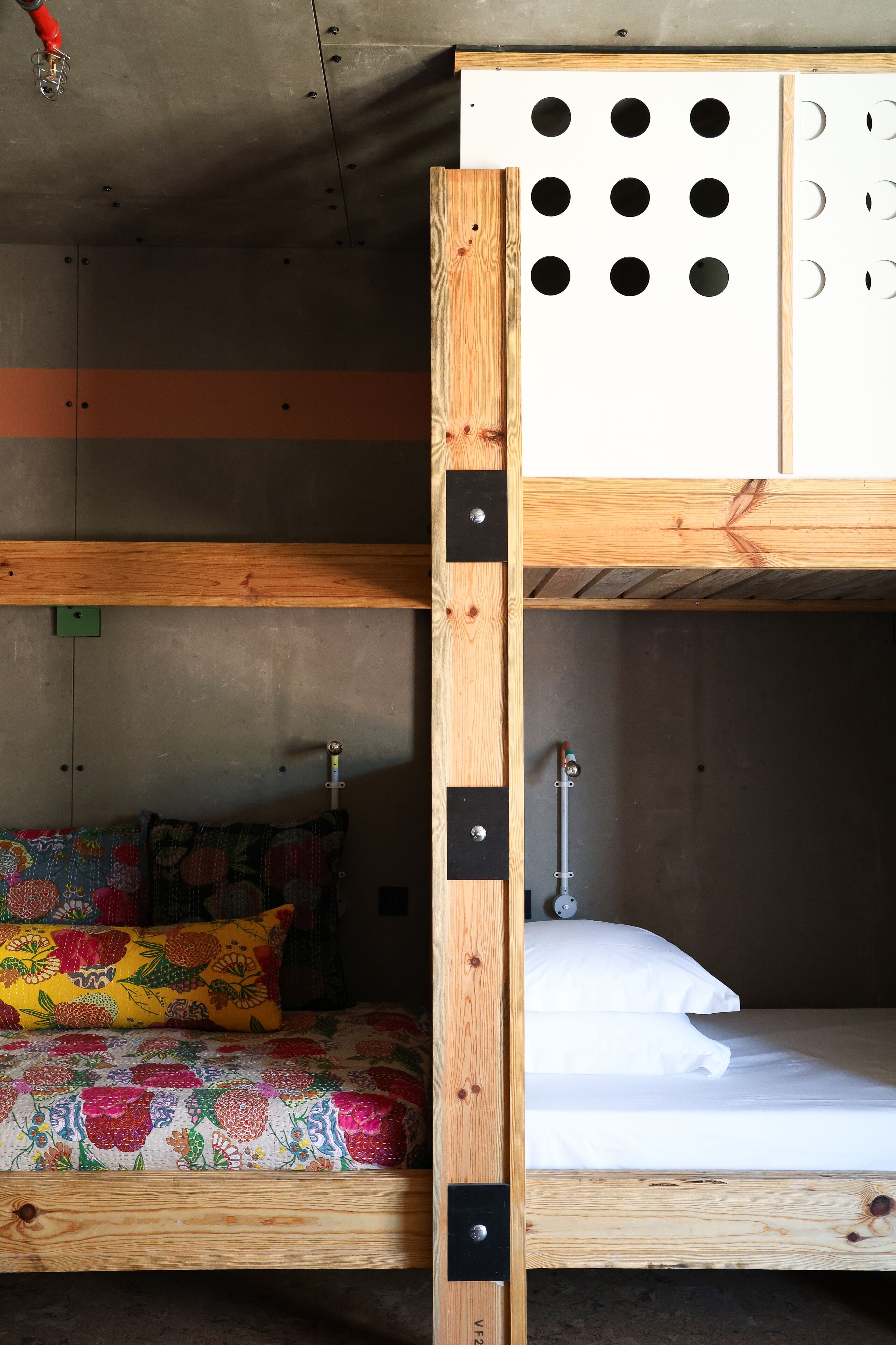 Een stapelbed met een onderbed voorzien van een kleurrijke deken en een bovenbed met een wit matras.