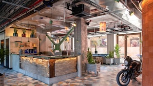 A reception area with a stone counter, potted plants, and a motorcycle. - Jam Hotel Lisbon (Lisbon)