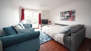 Ett modernt sovrum med en soffa, en säng, en tv och en tavla på väggen.