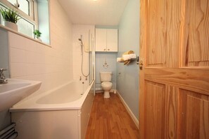 Ein Badezimmer mit Badewanne, Toilette und Holztür.