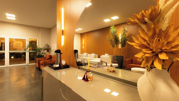 A hotel reception area with a modern design, featuring a reception desk, seating area, and a large plant. - Tri Hotel Executive Osório (Osorio)