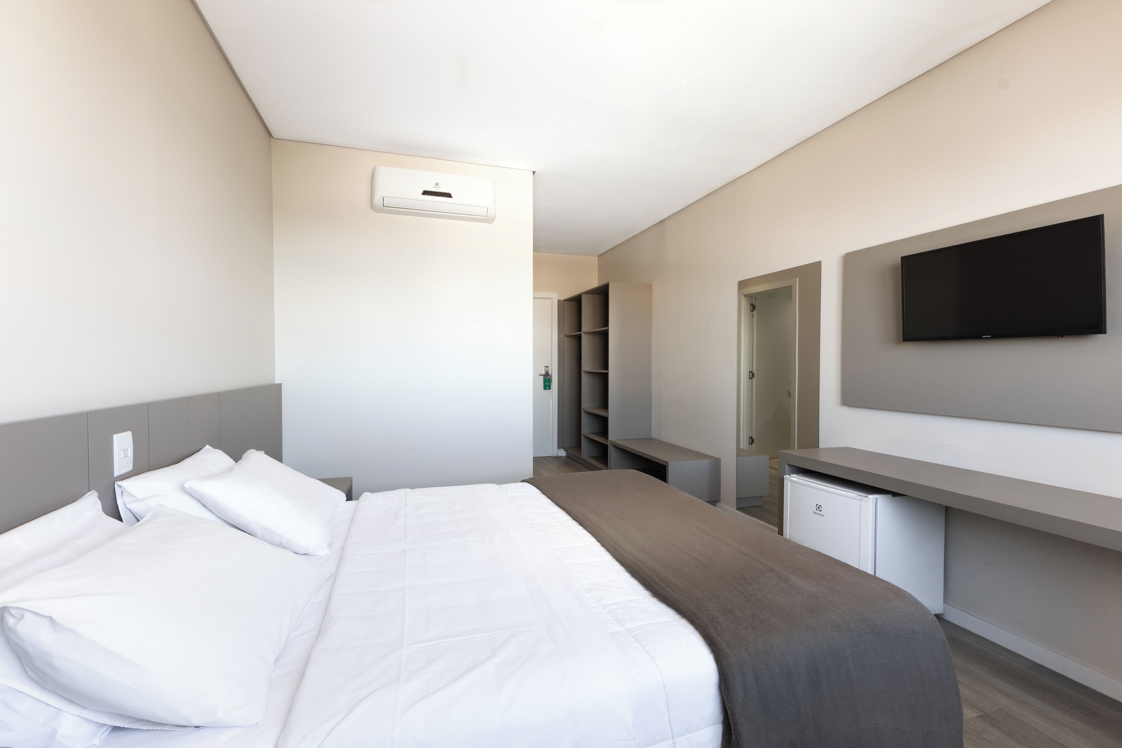 A hotel room with a bed, a desk, a television, and a wardrobe.