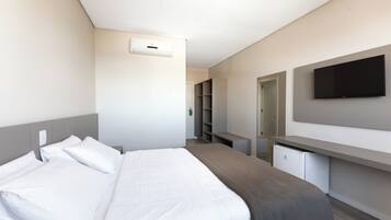 A hotel room with a bed, a desk, a television, and a wardrobe.