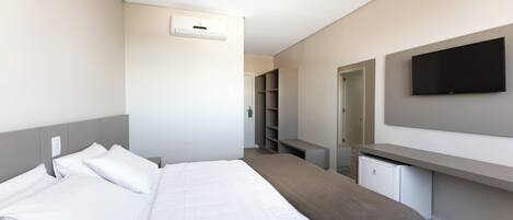 A hotel room with a bed, a desk, a television, and a wardrobe.