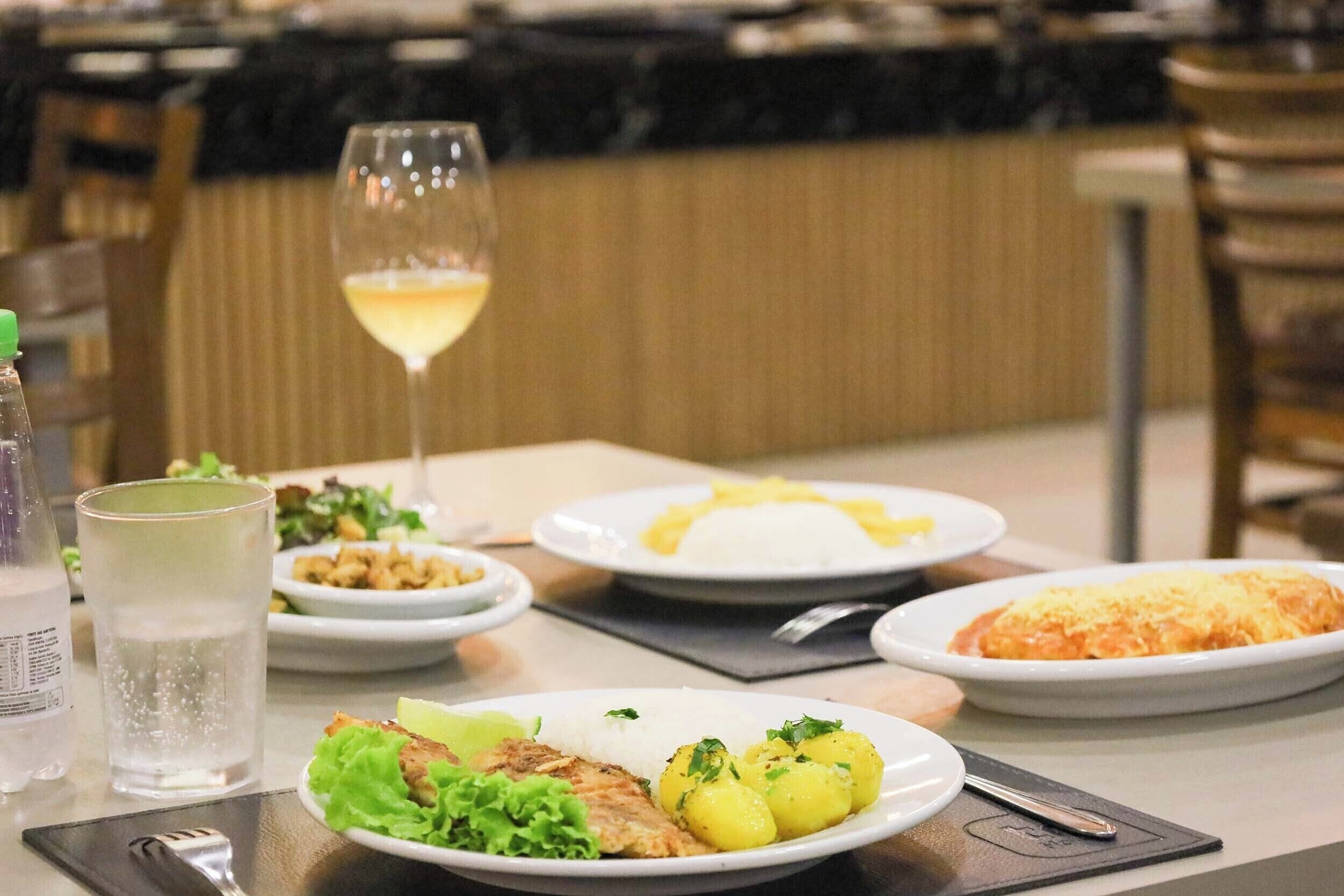 A dining table with plates of food, a glass of water, and a bottle.