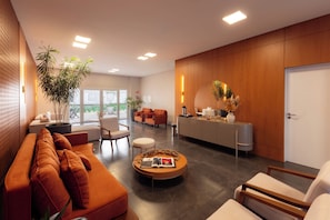 A modern living room with a sofa, chairs, a coffee table, and a reception desk. - Tri Hotel Executive Osório (Osorio)
