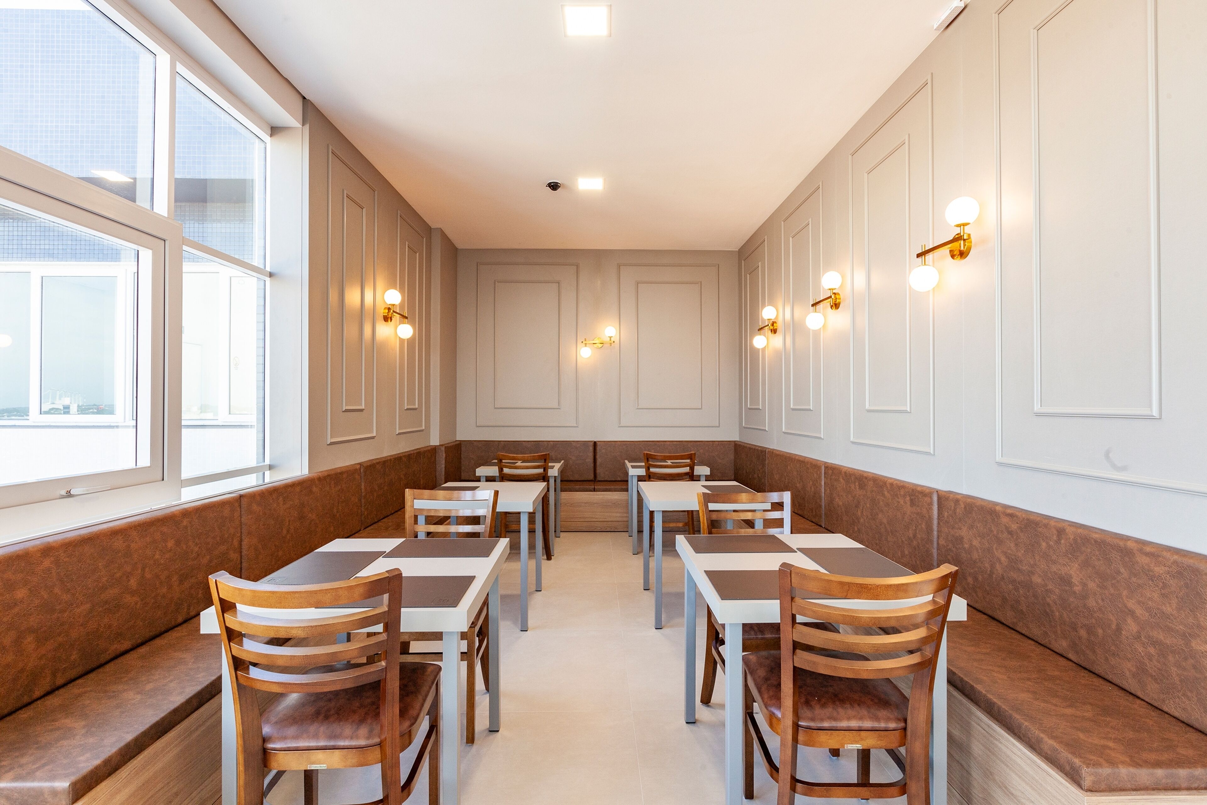 Ein Restaurant mit Sitzboxen und Tischen, Holzstühlen und Wandleuchten.