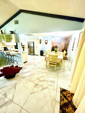 A dining area with a table and chairs, a kitchen with a refrigerator, and a dining table with chairs.