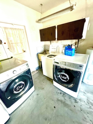 A laundry room with two washing machines, a dryer, and a blue water heater.